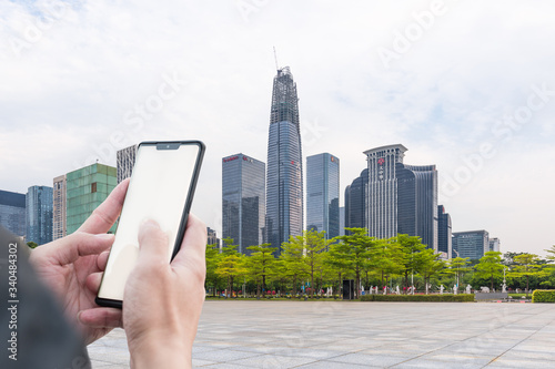 CBD buildings in Shenzhen and hands holding mobile phones