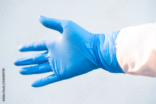 Hand put blue glove on white background.
