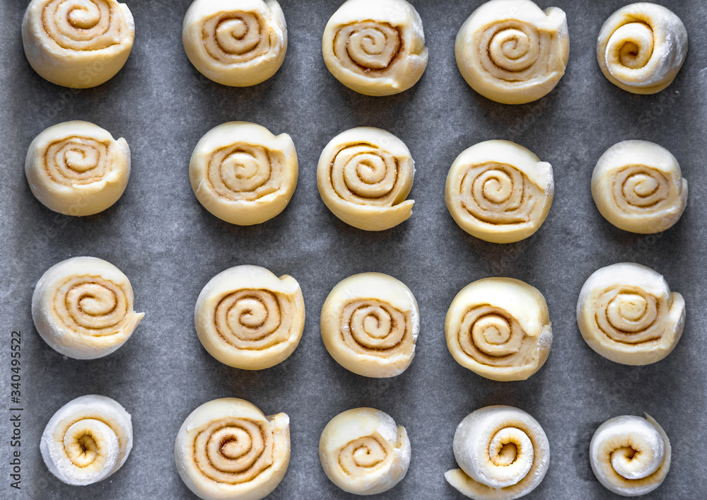 Fototapeta premium Pattern of raw cinnamon rolls, arranged on a baking tray.