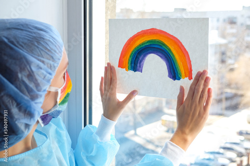 Portrait of a doctor in a mask, on which a rainbow is drawn as a sign of hope of victory over a coronovirus infection photo