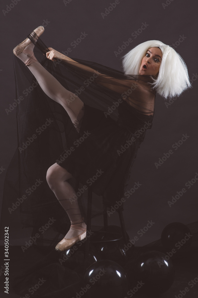 A woman ballerina wearing a black dress and white wig