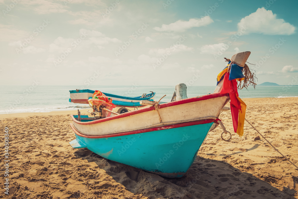Fototapeta premium Vintage fishing boat on the beach at sunset time with sky and the sea on the background.