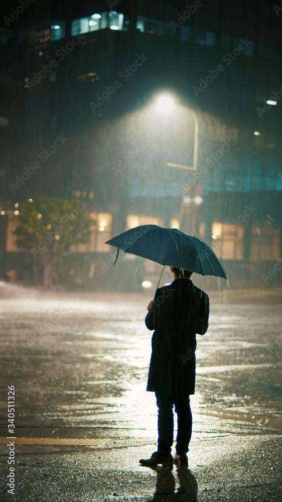 New coronavirus, man with umbrella standing in the rain, empty street at  night фотография Stock | Adobe Stock