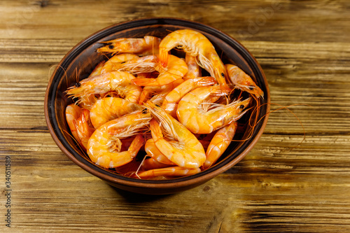 Fresh raw shrimps in a ceramic bowl on a wooden table