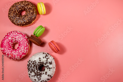 Tasty donuts and macaroons on pink background. Top view, copy space