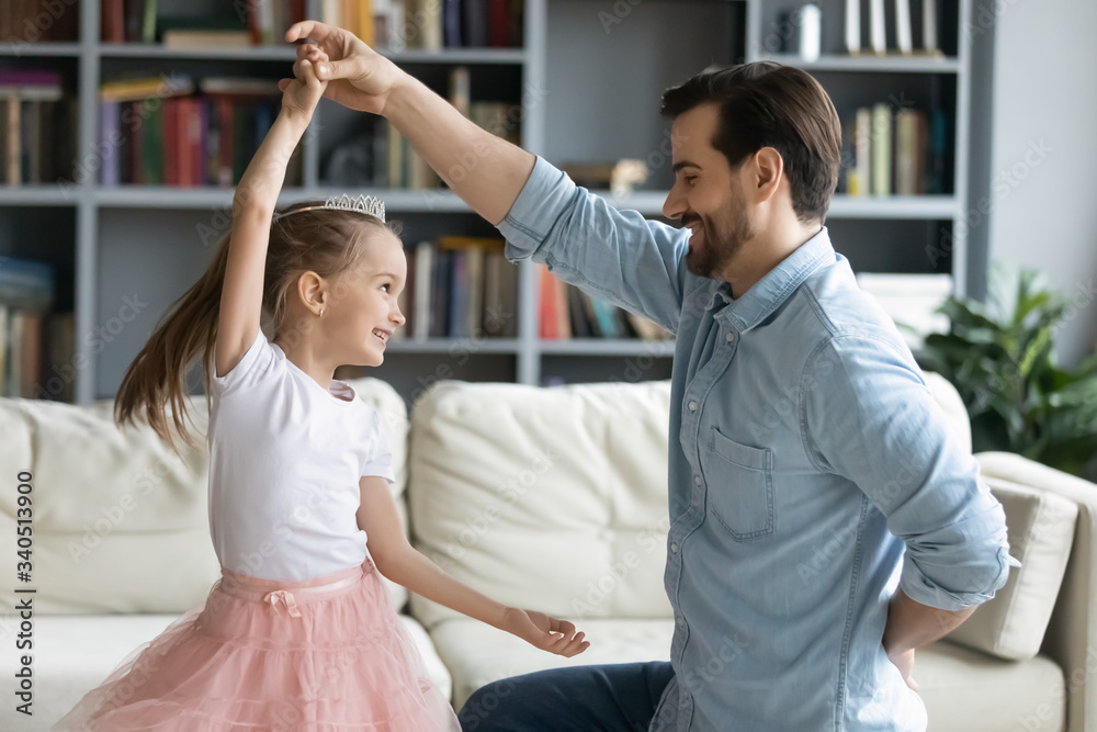 Loving caring father standing on one knee holds little daughter by the hand  while she spins.