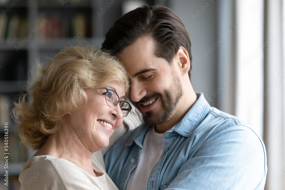Millennial son elderly mum hugging standing indoors, grown up child feels gratitude and love for mom, congratulations Mothers Day, 8 eight march holiday, family ties and bonding close up concept image Millennial son elderly mum hugging standing indoors, grown up child feels gratitude and love for mom, congratulations Mothers Day, 8 eight march holiday, family ties and bonding close up concept image