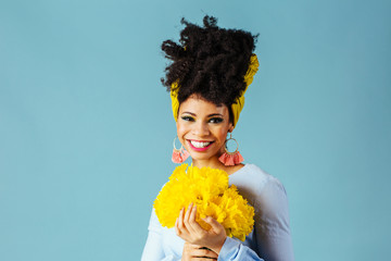 Portrait of a very happy young woman in blue holding bouquet of fresh yellow daffodils, isolated on blue background