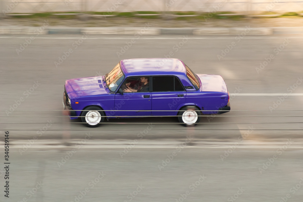 Aerial view of fast moving shiny blue car on the road. speeding in the city concept. Old school auto driving fast on highway with motion blur effect