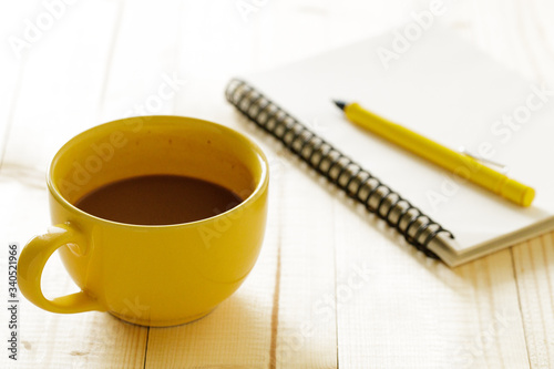 cup of hot chocolate on wooden background with notebook. Work from home concept.