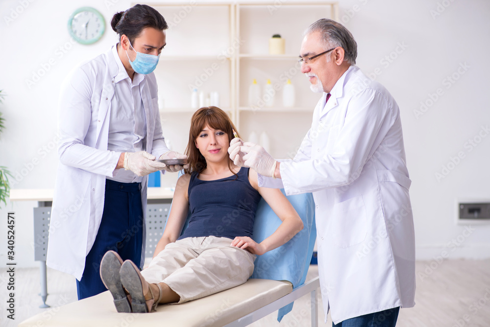 Two male doctors and young woman in plastic surgery concept Two male doctors and young woman in plastic surgery concept