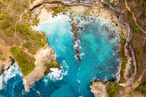 Top down aerial view of waves breaking inside a small rocky bay (Blue Lagoon, Nusa Ceningan, Indonesia) photo