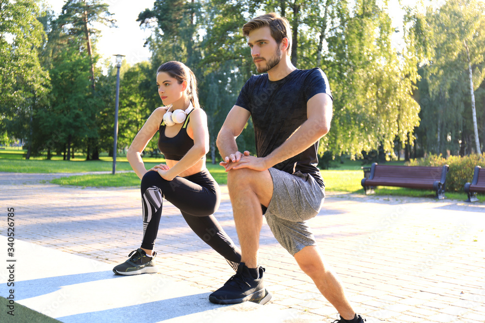 Obraz premium Happy young couple exercising together in a park.