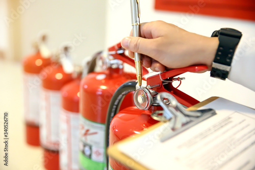 Canvas Print Fireman are checking and inspection red tank of fire extinguisher