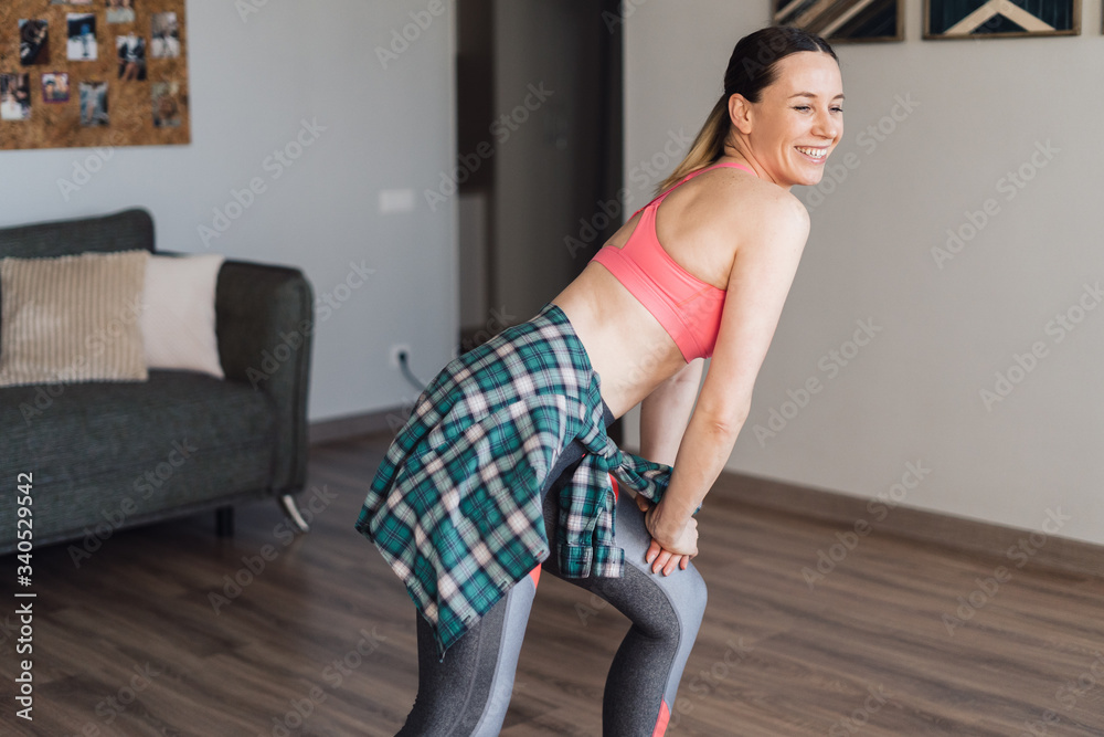 Active young woman in sportswear clothes dancing in living room with cozy, modern interior, enjoy life concept. Occupation during isolation at home. Active young woman in sportswear clothes dancing in living room with cozy, modern interior, enjoy life concept. Occupation during isolation at home.