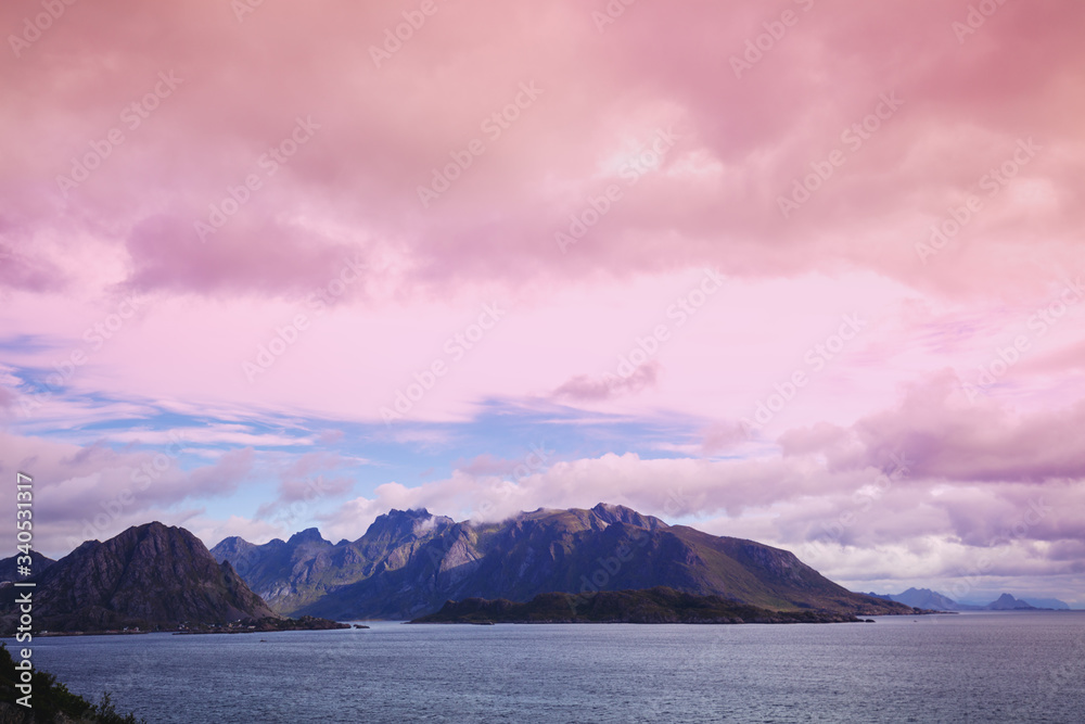 Island on the horizon. Rocks in the sea. Beautiful rocky sea landscape in evening. Wild nature Norway, Lofoten islands seascape. Gradient color