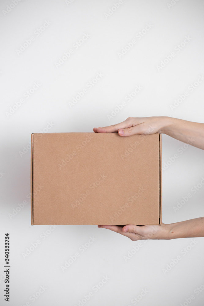 A parcel cardboard box in a delivery man hands on a white background. Delivery service concept. A parcel cardboard box in a delivery man hands on a white background. Delivery service concept.