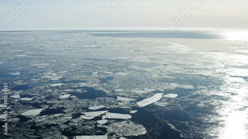 Flying backward over Baltic sea with floating ice floes, Holmsund locality, close to Umea city, Vasterbotten county, Sunny spring day, quiet weather photo