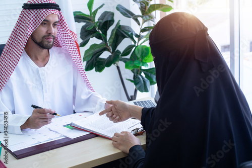 Arabia businessman sitting to consulting with  Arabia woman in office, woman wearing Niqab and pointing her finger