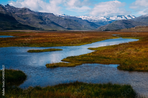 calm river in a field against the backdrop of mountains in iceland
