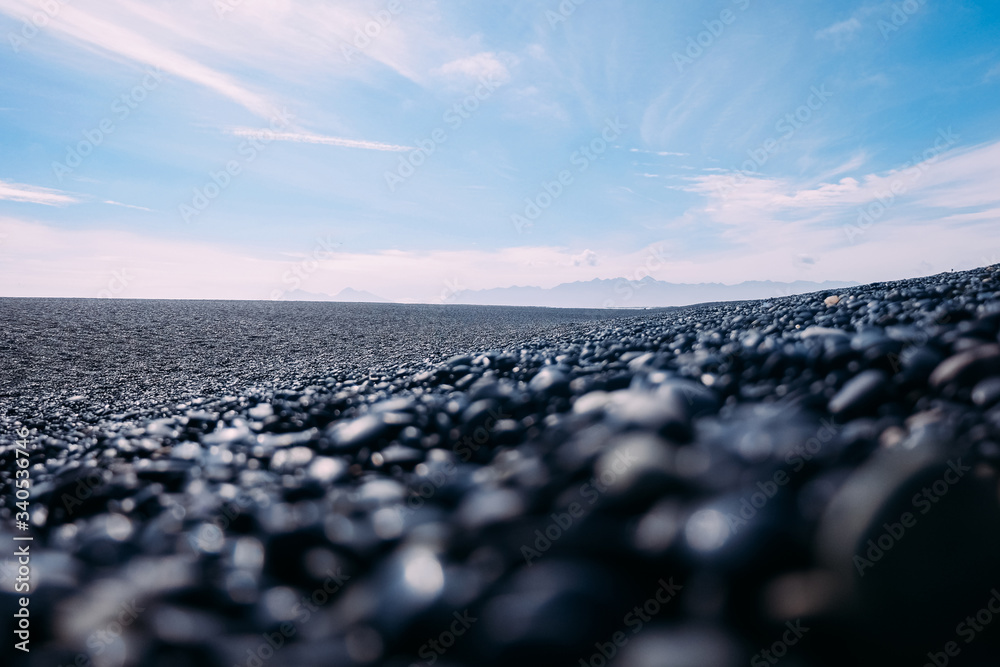 Fototapeta premium black pebble beach in iceland in perspective and blue sky in the afternoon