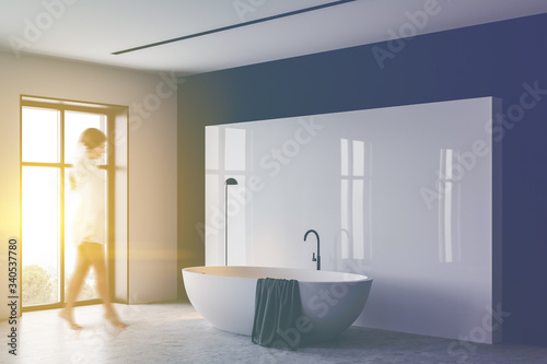 Woman walking in white and black bathroom with tub