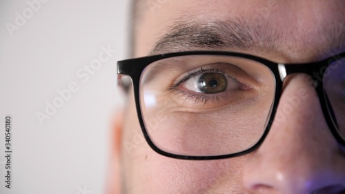 Close-up face of a male eyes with glasses looks at the camera and smiles. Portrait of a young man programmer with glasses. Quarantine