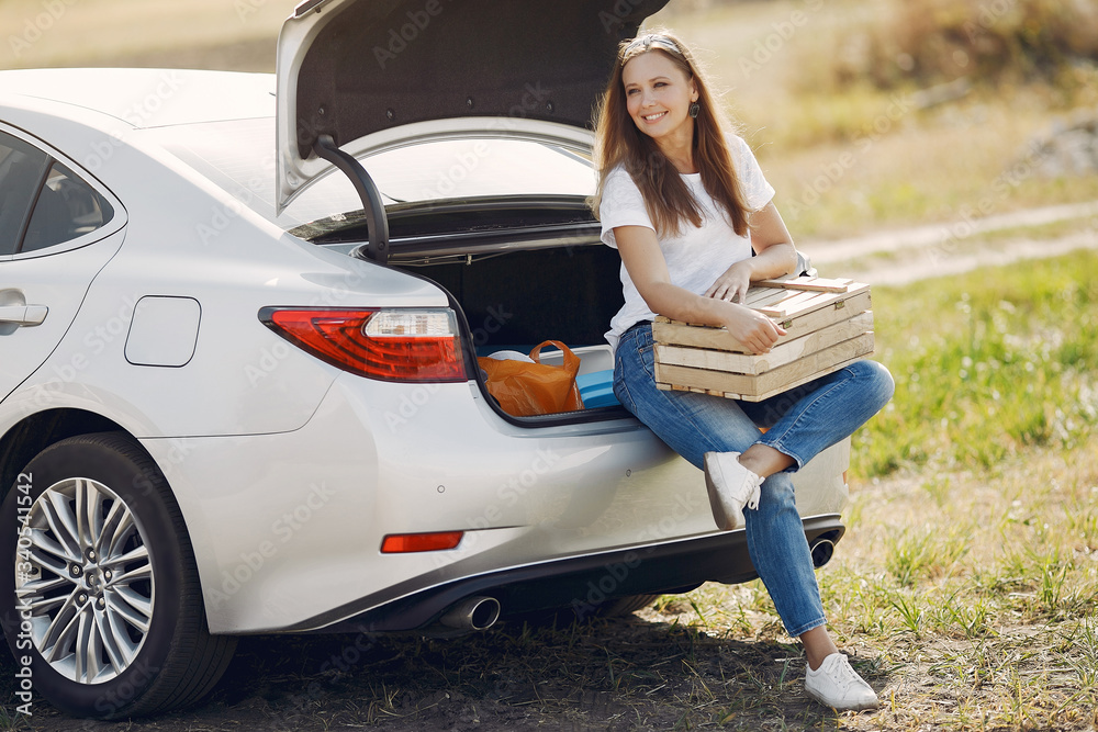 Woman by the car. Lady in a white t-shirt. Woman with wood box.