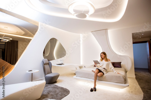 Fotografia Young woman with tablet sitting in the luxurious apartment