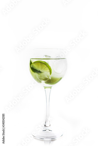 Rum based cocktail with lime in wine glass (variation of cuba libre) on the white background. Selective focus. Shallow depth of field. 