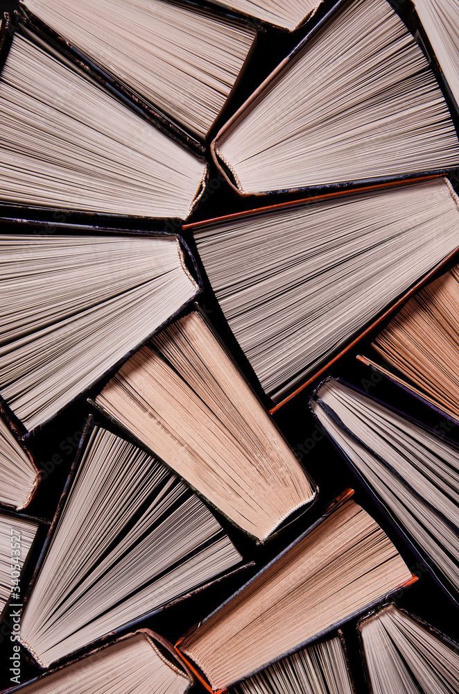 Fototapeta premium Many open old multicolored books stand on the bookshelf