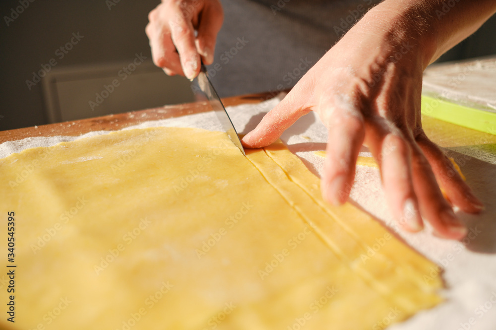 Obraz premium Close up woman hands, cutting dough in the sunlight on the table