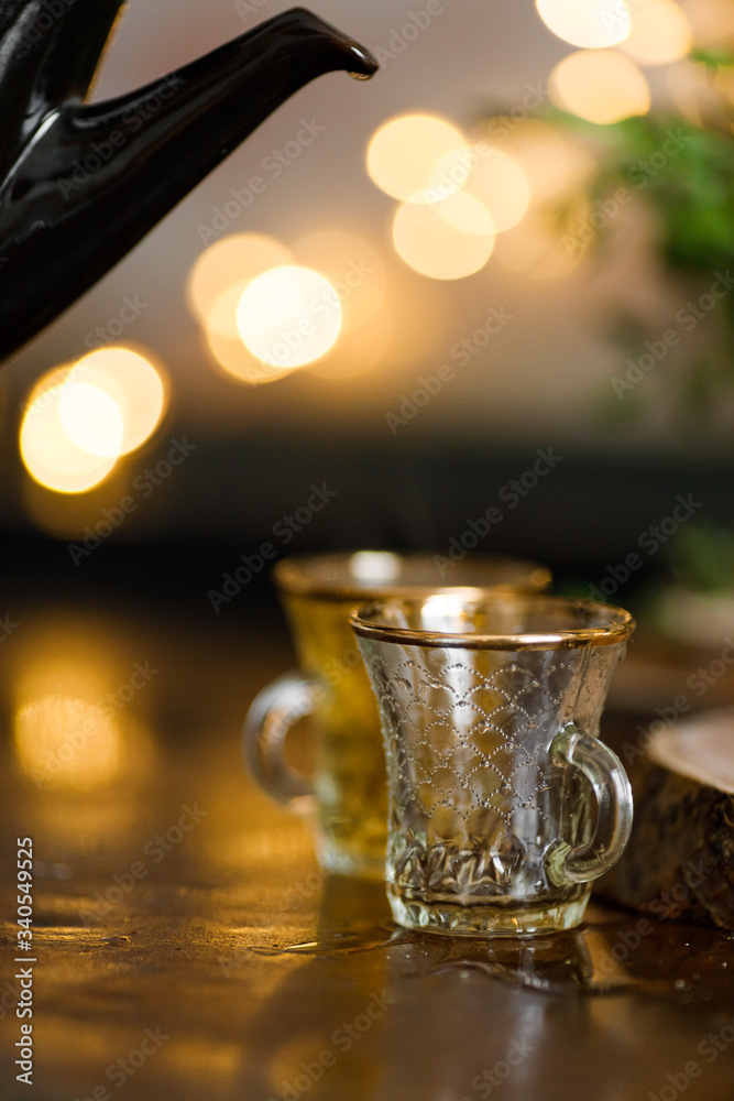 tea is poured into a turkish cup on the background of lights