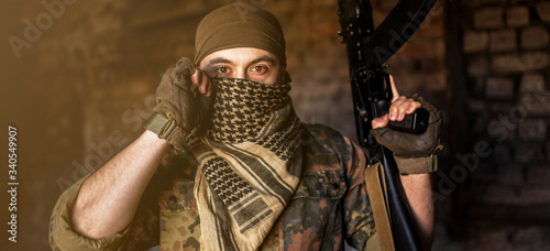 Arab male soldier in a headdress from the national keffiyeh with a weapon in his hands man with a gun on a black background