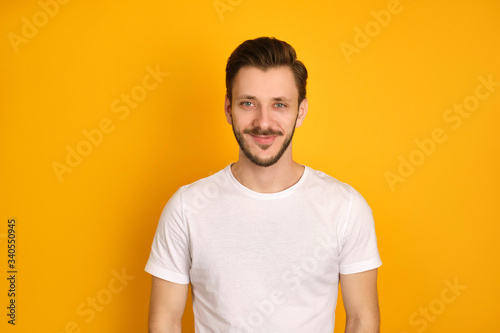 Colorful portrait of a handsome man dressed in white t-shirt on the yellow background