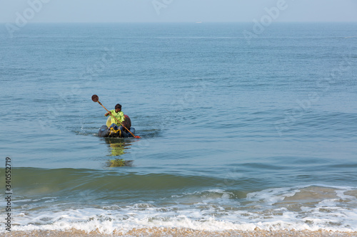 Mararikulam, Kerala - January 6, 2019: Fisherman paddling to shore on his boat in Marari Beach in Mararikulam kerala india