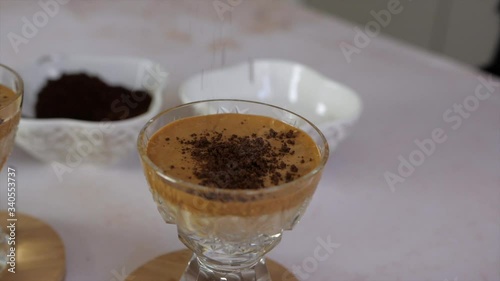 Closeup of cocoa grains falling on delicious foamy dalgona coffee, slow motion photo