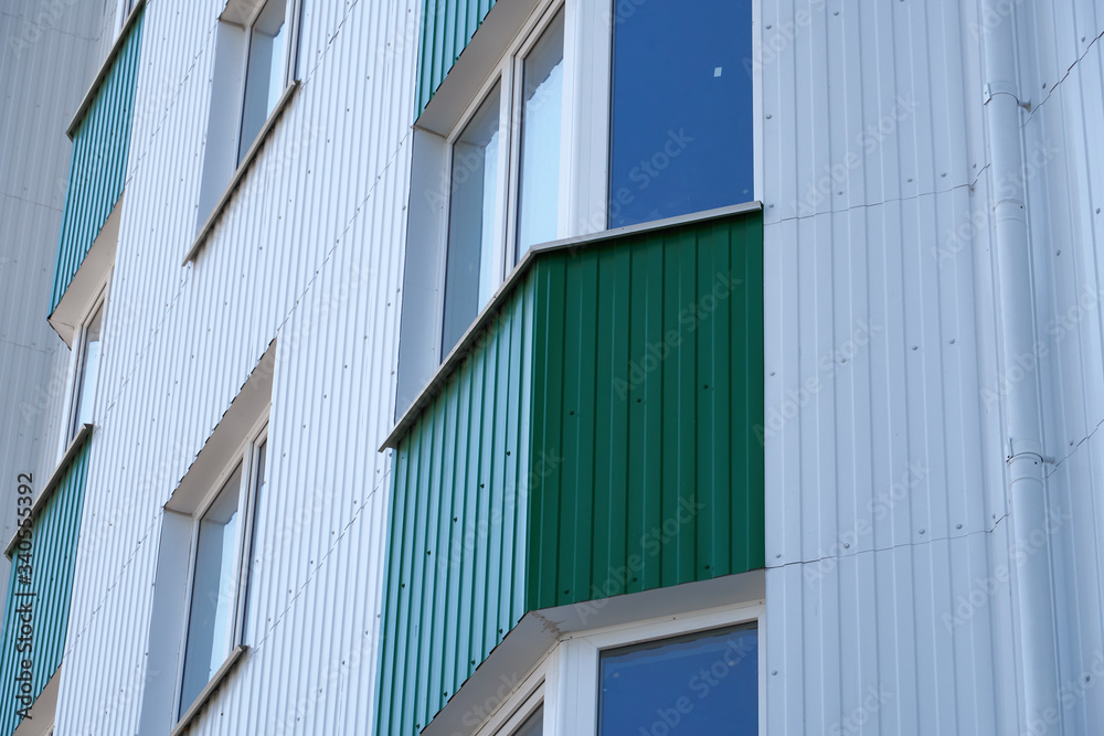 facade of a new multistory building with white and green metal siding, many Windows facade of a new multistory building with white and green metal siding, many Windows