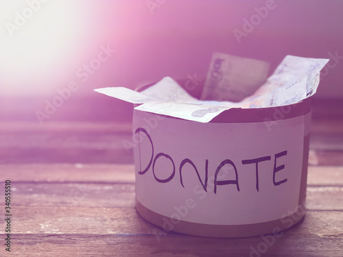 Fototapeta Naklejka Na Ścianę i Meble -  Donation for prevented virus covid-19 Concept.Donate box has hygienic medical masks on wood table top,for help the underprivileged or medical personnel,dimly light,with lens flare,selective focus.