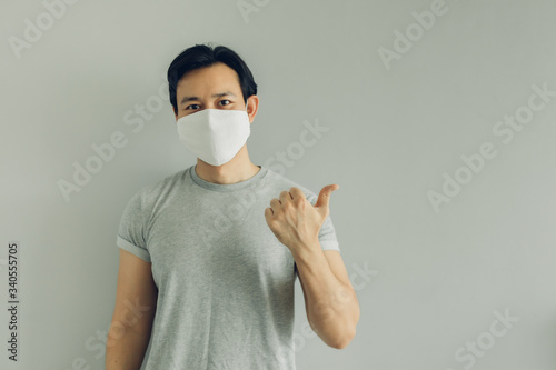 Normal face of Asian man wearing white hygienic mask in grey t-thirt with copy space.