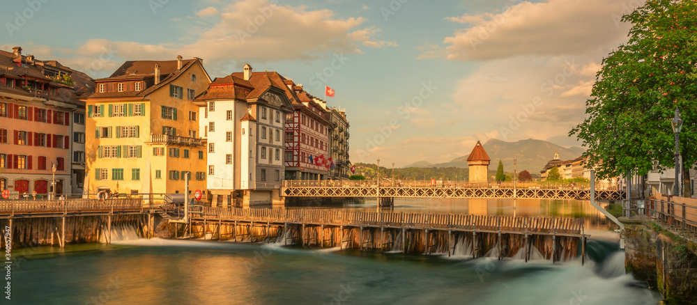 Naklejka premium Panoramic evening view of popular tourist attraction with historic Chapel bridge. Spectacular spring cityscape of Lucerne. Stunning outdoor view of Switzerland, Europe. Traveling concept background.