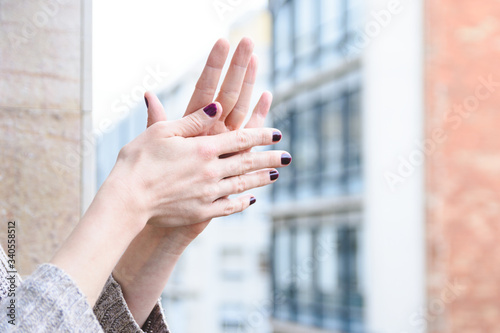 woman hands clapping healthcare staff on balcony during confinement