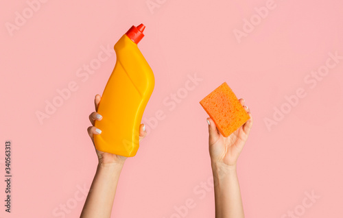 Cleaning service. Close up of girl holding toilet desinfectant gel and sponge on pink background, copy space
