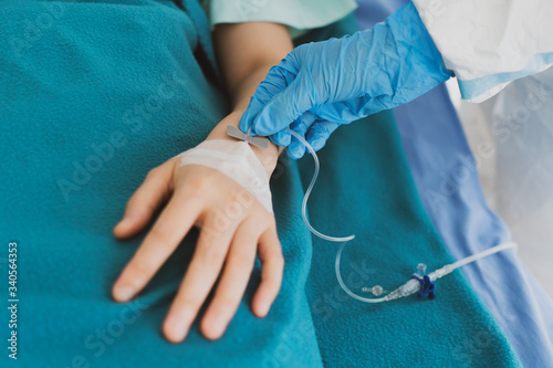 close up picture of doctor wearing gloves giving intravenous fluid to the critical patient with covid-19 or coronavirus infection. medical concept (fouus at doctor's hand)
