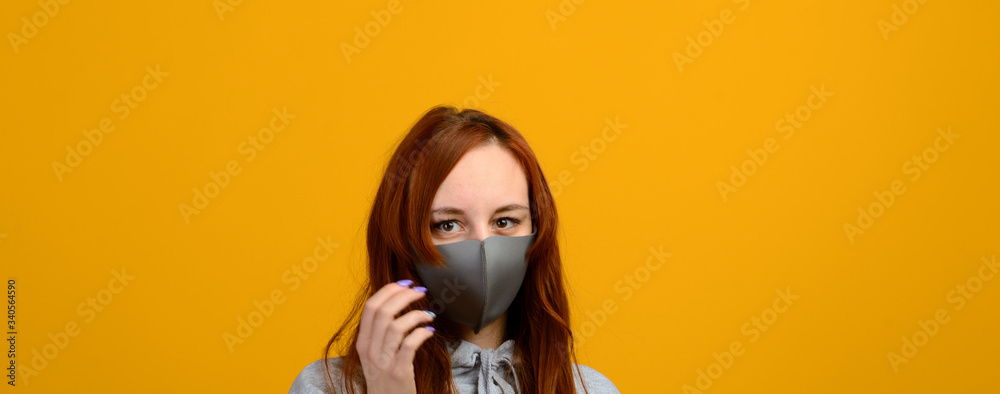 Portrait of a girl in a mask, which puts on a rubber glove. Yellow background. Portrait of a girl in a mask, which puts on a rubber glove. Yellow background.