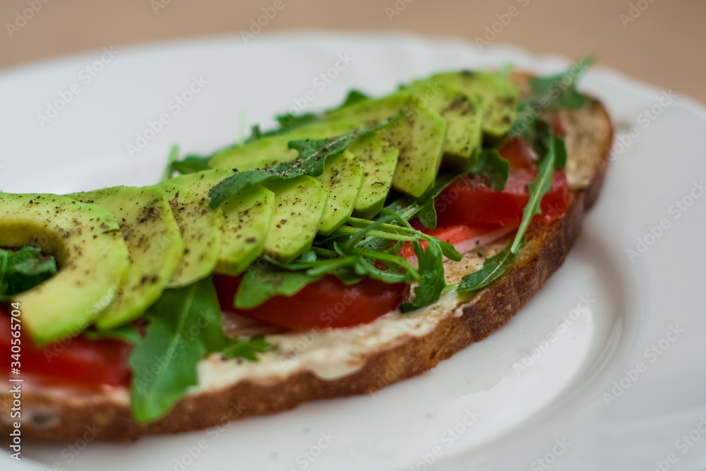 Toast of dark bread, avocado with tomato and arugula. Healthy food, breakfast of fresh vegetables.