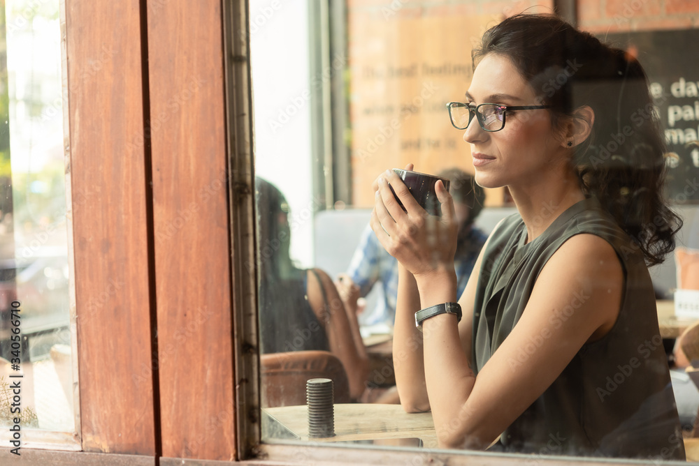 Beautiful woman have coffee in cafe while work in morning look out the window while thinking of the future Beautiful woman have coffee in cafe while work in morning look out the window while thinking of the future
