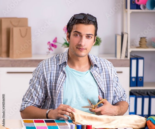 Young handsome tailor working in his workshop