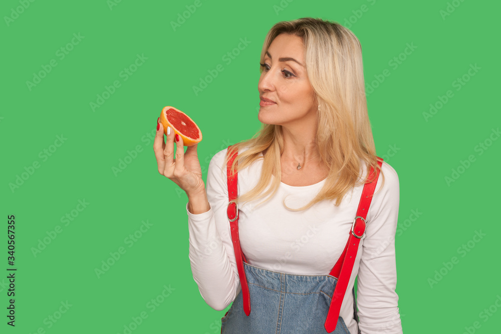 Detoxing food, vitamins for diet. Portrait of pensive adult woman looking at sliced juicy fresh grapefruit with thoughtful expression, healthy nutrition. studio shot isolated on green background Detoxing food, vitamins for diet. Portrait of pensive adult woman looking at sliced juicy fresh grapefruit with thoughtful expression, healthy nutrition. studio shot isolated on green background