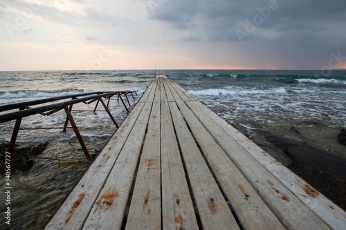 wooden bridges leading out to the sea at sunset, dark sky before a thunderstorm, a place for fishing and meditation